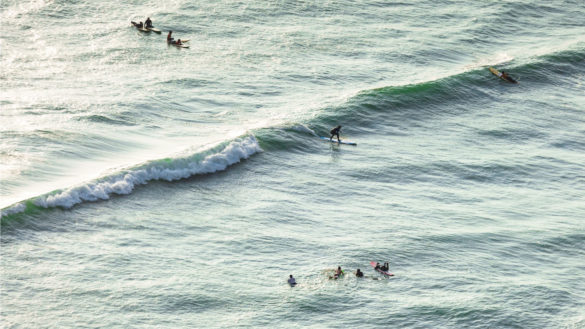 Surfisti in acqua sulle onde lunghe e ordinate di Huanchaco, viste dall'alto