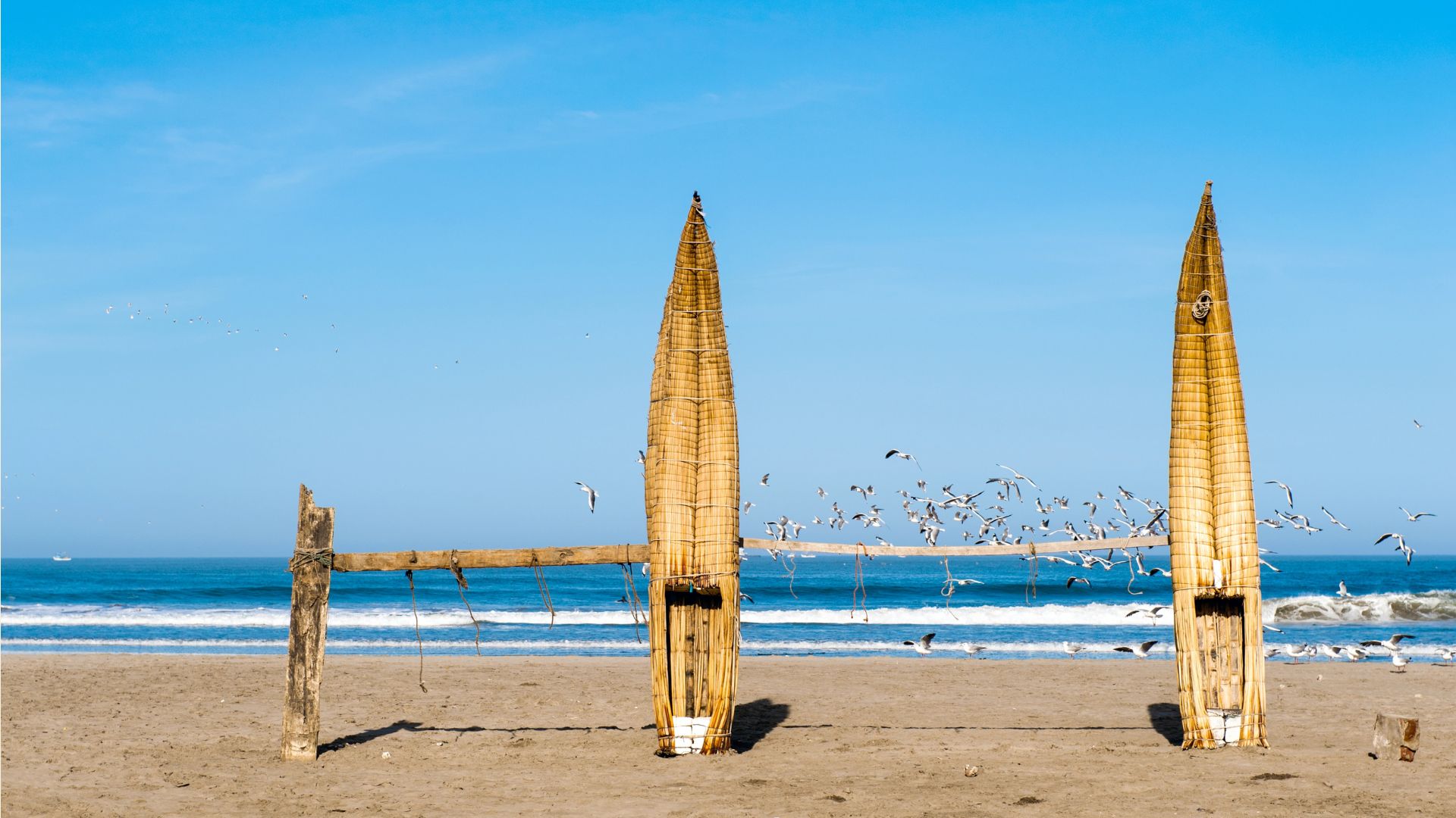 Caballitos de totora appoggiati in piedi sulla spiaggia di Huanchaco