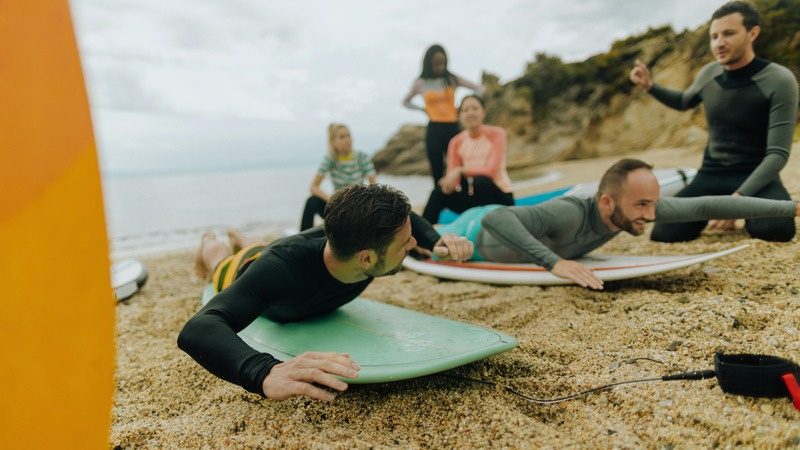 Prima lezione di surf sulla spiaggia, coach e allievo con la tavola
