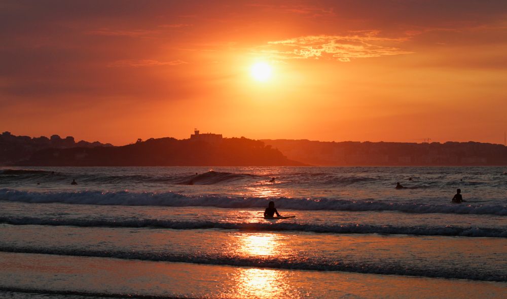 Surfisti in acqua al tramonto a Somo, nel nord della Spagna