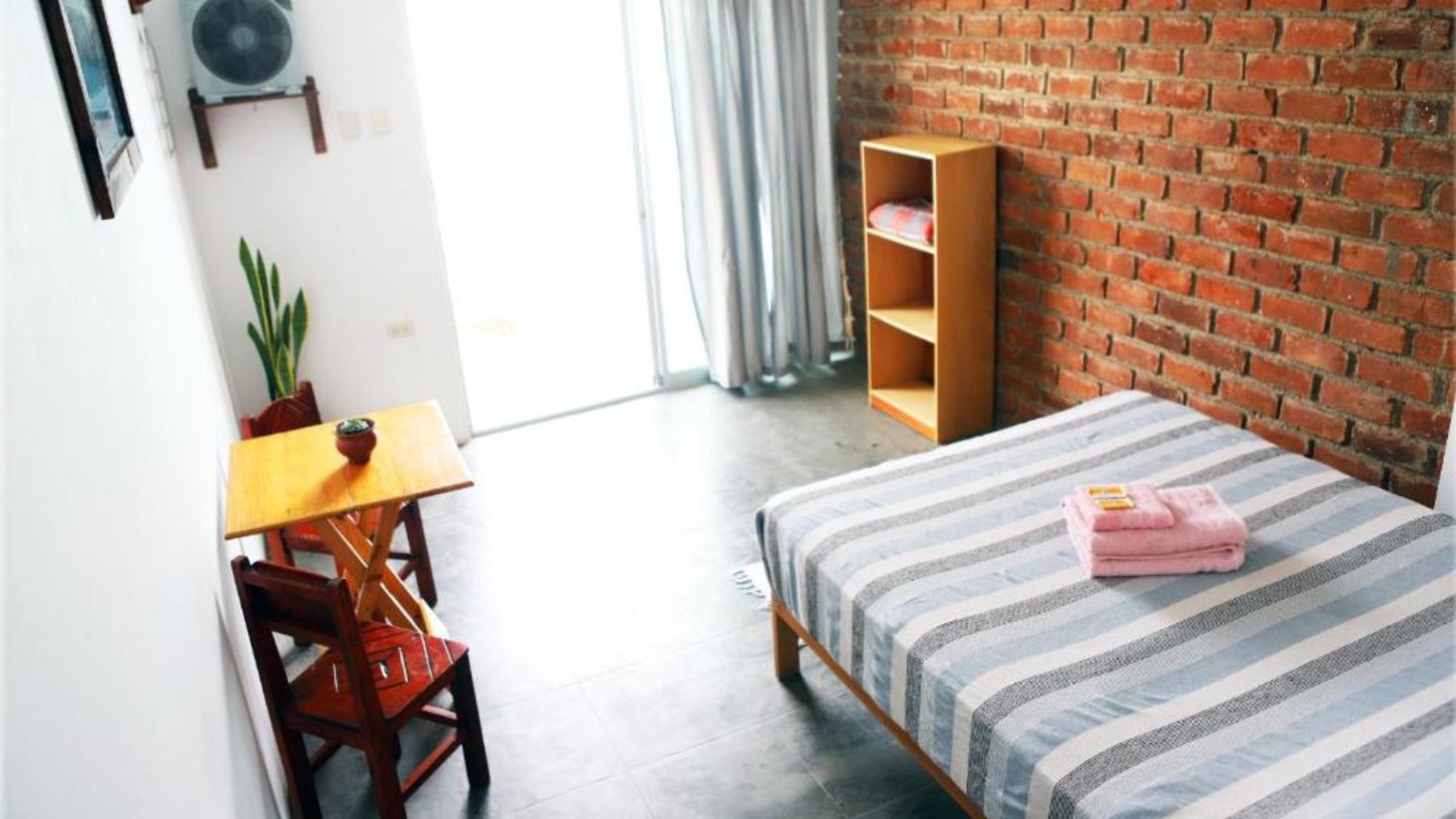 La camera matrimoniale con il letto e la parete in mattoni