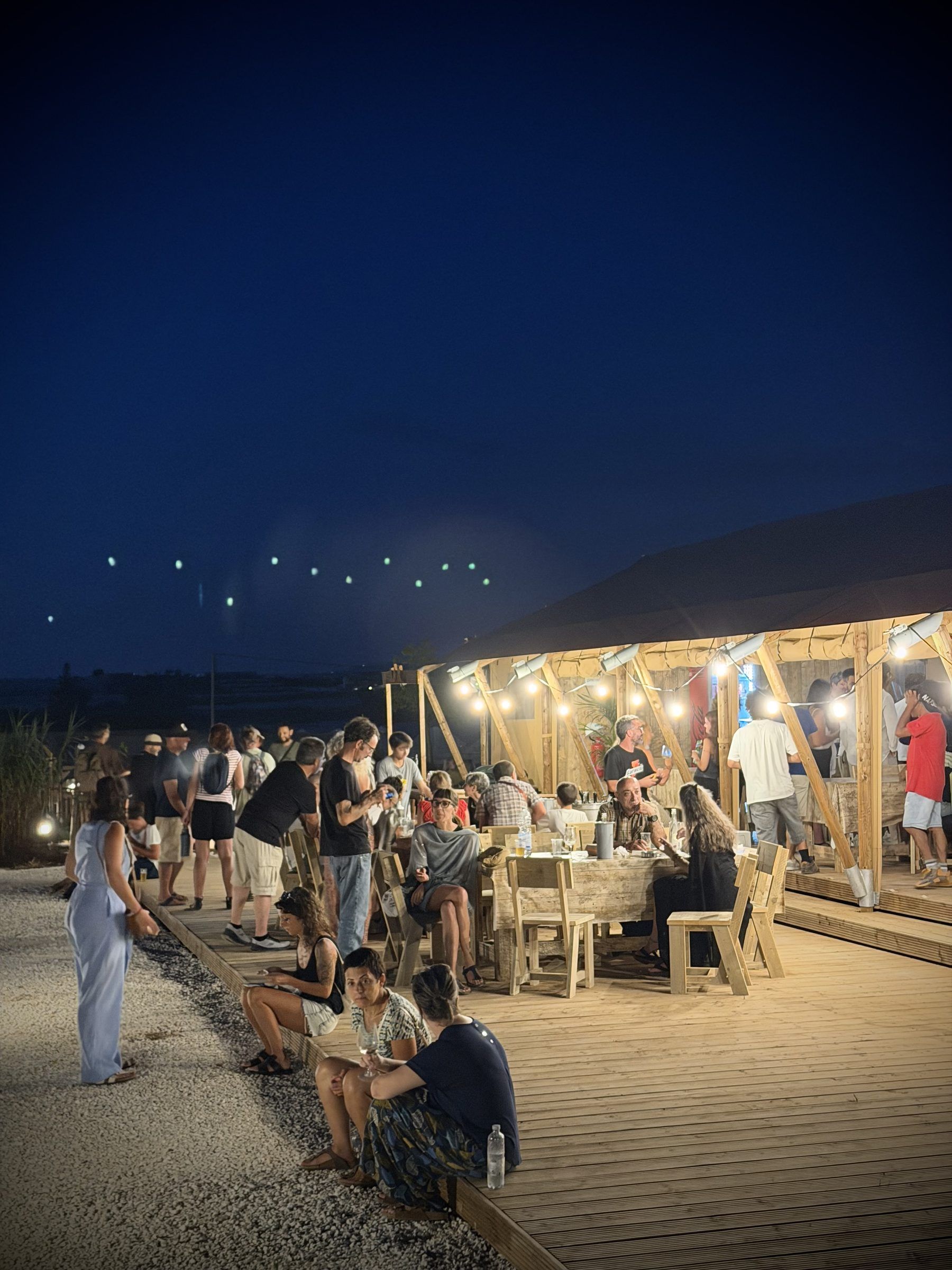 Cena in spiaggia con falò acceso e persone intorno al fuoco