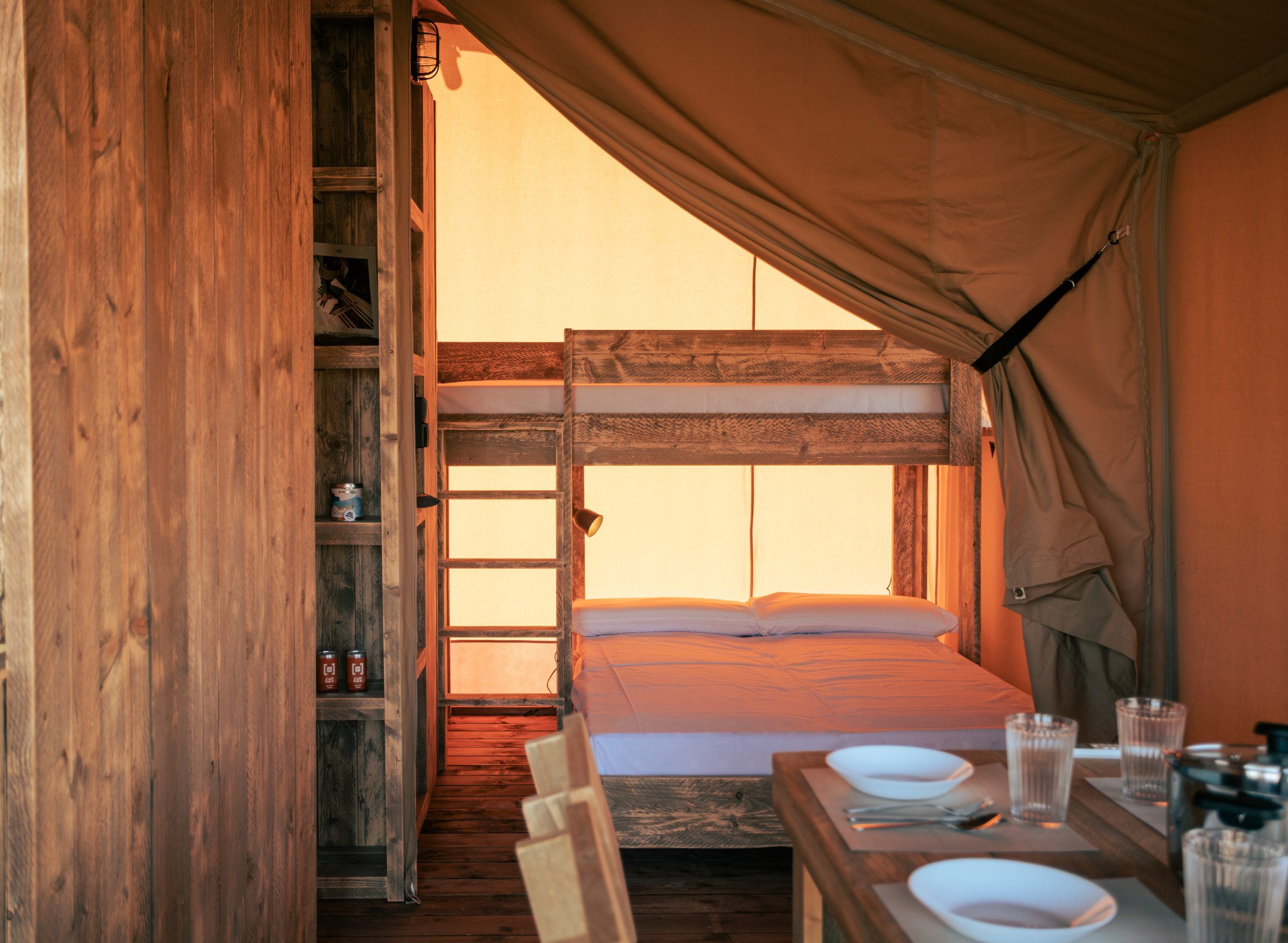 Interno di una tenda glamping luxury con letto e legno